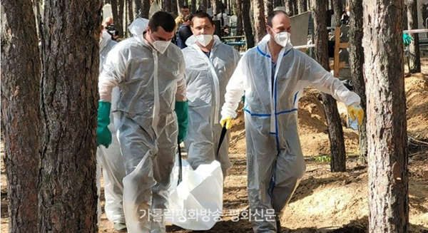 우크라이나 구조대원들이 이줌 외곽 숲 민간인 집단매장지에서 시신을 발굴해 옮기고 있다. 바티칸 뉴스 갈무리 