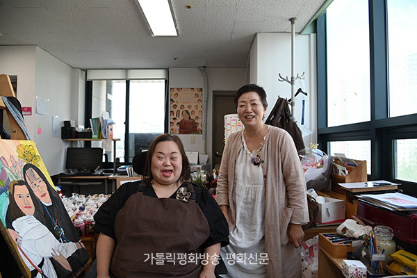 									정은혜(왼쪽) 작가와 어머니 장차현실 작가가 인터뷰 후 사진 촬영을 하며 환하게 웃고 있다. 								