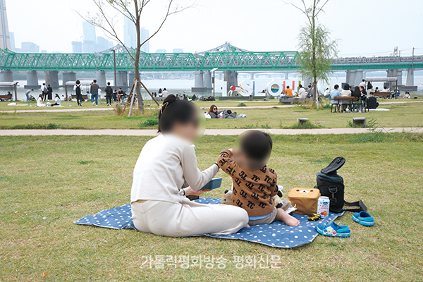 									오랜만에 나들이에 나선 청소년한부모 한주현씨와 두 살 아들 수언이가 한강변 잔디밭에 앉아 깁밥을 먹고 있다. 								