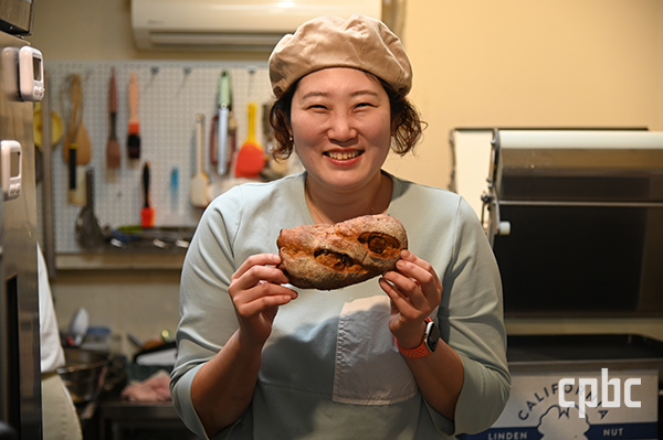 '까사드선주' 사장 신선주씨가 직접 만든 빵을 들고 미소를 짓고 있다. 																	
